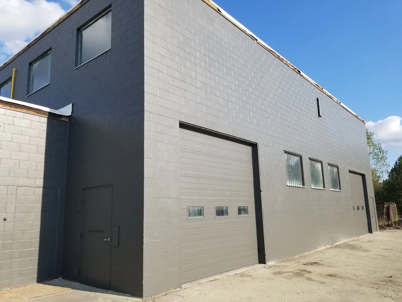 Professionally painted commercial building exterior with grey masonry walls and overhead garage door by GreenTech Painting in London, Ontario.