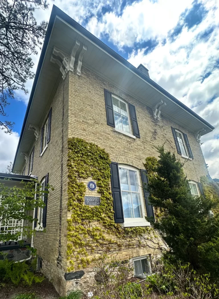 Historic brick home in London, Ontario featuring restored exterior trim, shutters, soffits and decorative architectural details.