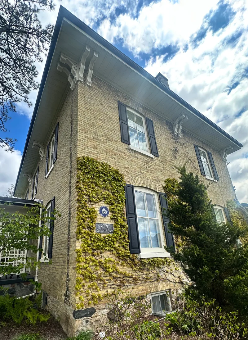 Historic brick home in London, Ontario featuring restored exterior trim, shutters, soffits and decorative architectural details.
