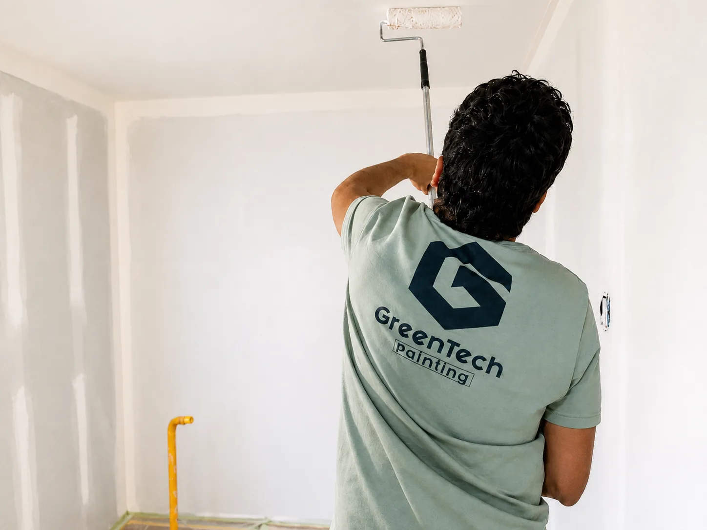 Professional painter applying premium white paint to interior walls and ceiling during a residential painting project by GreenTech Painting in London, Ontario.